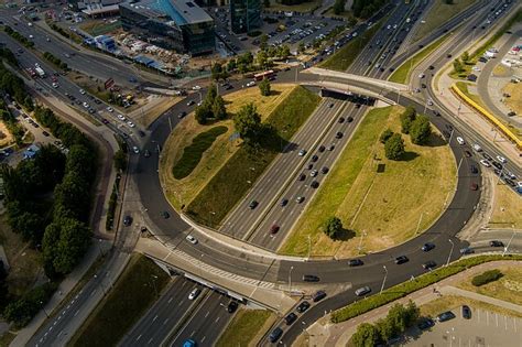 Teminė nuotrauka: žiedinė sankryža iš viršaus, su scheminiais automobilių srautais ir pėsčiųjų takais