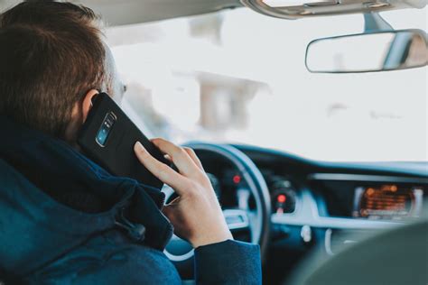 Tematinė nuotrauka: vairuotojas naudojasi telefonu laikiklyje navigacijai