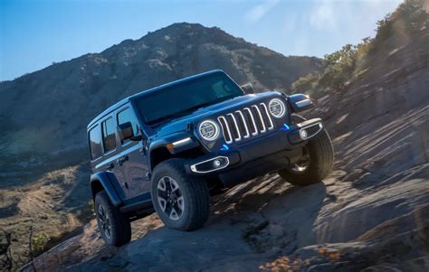 Jeep Wrangler 4xe driving through rugged terrain