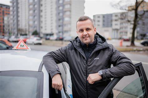 Thematinė nuotrauka: besimokantis vairuoti asmuo su instruktoriumi, vakare arba savaitgalį, pabrėžianti lankstumą