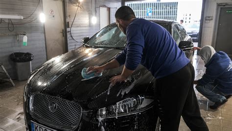 Tematinė nuotrauka: darbuotojas plauna automobilį rankomis