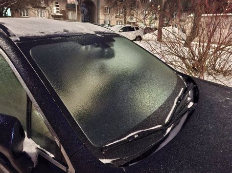 Automobilio stiklai, padengti ledu ir tirpstančiu vandeniu