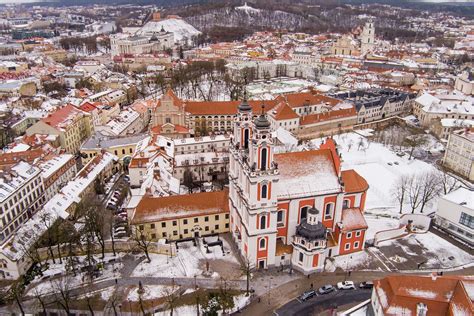 Vaizdas su keliais skirtingų klasių automobiliais, stovinčiais ant Vilniaus senamiesčio fono