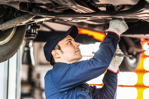 Tematinė nuotrauka: automobilio važiuoklės remontas autoservise, mechanikas su įrankiais