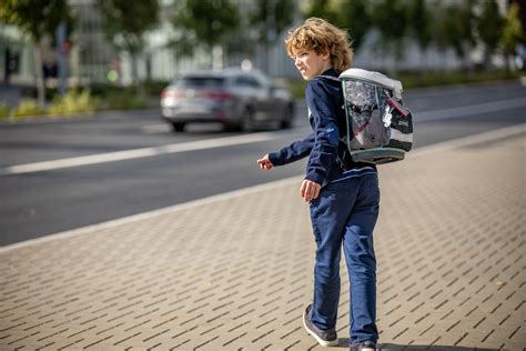 Vaikas su tėvais eina per pėsčiųjų perėją, atidžiai stebėdami eismą