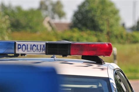 Teminė nuotrauka, vaizduojanti automobilį su valstybiniais numeriais ir modernia policijos įranga, tikrinančia duomenis