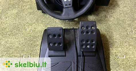 Tematinė nuotrauka: kompiuterinis vairas su pedalais ir žaidimų konsolė