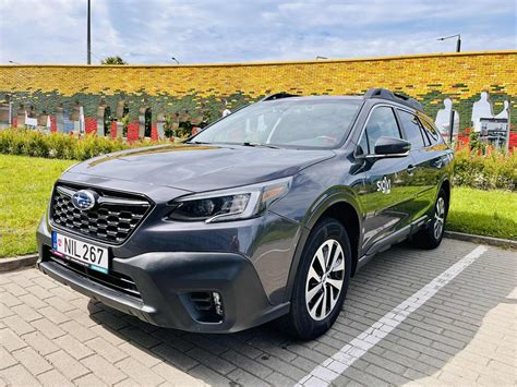 Nuotrauka automobilio Subaru Outback su atidarytu bagažine ir gamtos fone