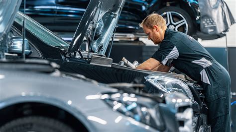 Mechanikas atlieka kompiuterinę diagnostiką automobiliui su atidarytu variklio dangčiu