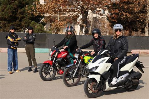 Jauni žmonės su šalmais ant motorolerių, besimokantys vairuoti