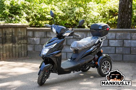 Nuotrauka, vaizduojanti modernų elektrinį triratį motorolerį su dviem sėdynėmis ir stogeliu.