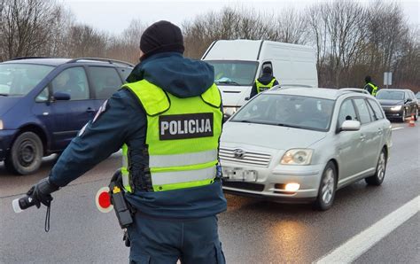 Ilustracija, kaip pareigūnas signalizuoja sustabdyti transporto priemonę tamsiuoju paros metu, dėvint šviesą atspindinčią liemenę.