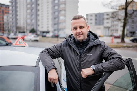Teminė nuotrauka: besišypsantis vairavimo instruktorius šalia mokinio automobilyje