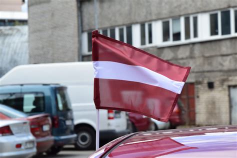Tematinė nuotrauka, vaizduojanti automobilių turgų arba internetinį automobilių pardavimo portalą su Latvijos vėliavos elementais