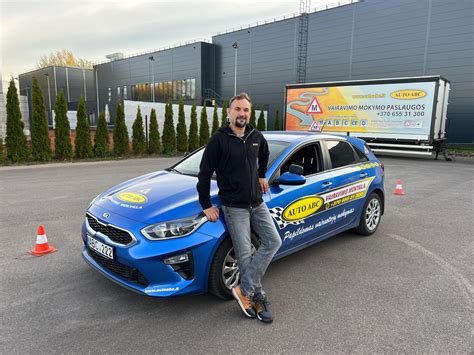Teminė nuotrauka: besišypsantis studentas ir instruktorius automobilyje po sėkmingo vairavimo egzamino