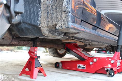 Safety gear for car maintenance: gloves, safety glasses, car on jack stands