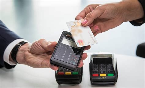 Žmonės, atsisiskaitantys banko kortele prie keltų terminalo kasos