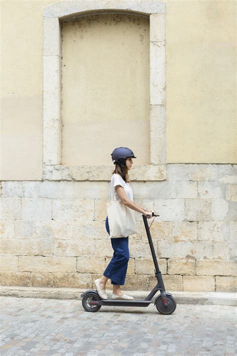 Pavaizduotas žmogus su šalmu ant paspirtuko, važiuojantis keliu