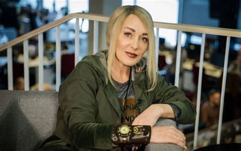Džordana Butkutė prie raudono „vabaliuko“ automobilio, besišypsanti