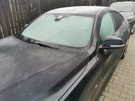 purškiklis su alkoholio tirpalu ir apledėjęs automobilio stiklas