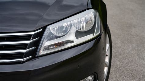 automobilis su įjungtais žibintais lyjant lietui tamsoje