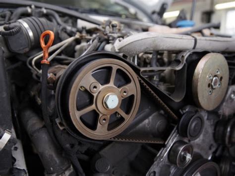 Nuotrauka, vaizduojanti susidėvėjusį ir naują automobilio diržo įtempėjo mechanizmą