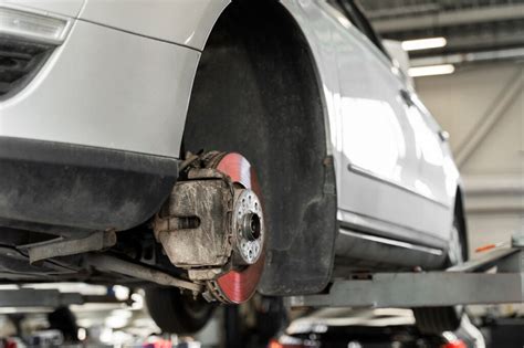 Nuotrauka automobilio pakelto ant keltuvo, demonstruojanti prieigą prie važiuoklės ir stabdžių sistemos elementų.