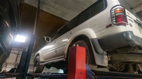 nuotrauka su autoserviso meistrais, dirbančiais su automobilio važiuokle