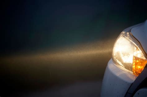 Teminė nuotrauka su automobilio priekiniais žibintais naktį, pabrėžiant matomumo svarbą