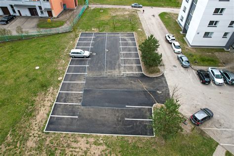 Automobilių stovėjimo aikštelė prie daugiabučio namo, pilna automobilių