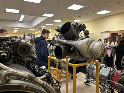 Tematinė nuotrauka: besimokantys studentai dirba su hibridinio automobilio variklio modeliu mokymo centre