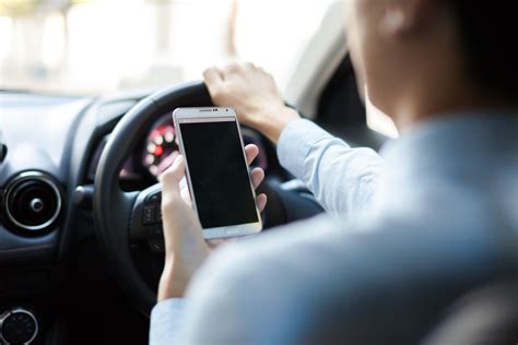 Vairuotojo, žiūrinčio į telefoną už vairo, nuotrauka