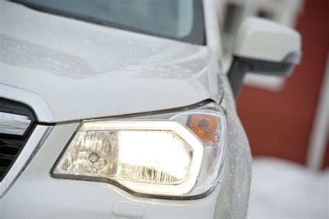 Teminė nuotrauka: Kia Sorento su įjungtais priekiniais žibintais važiuojantis keliu