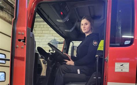 nuotrauka, vaizduojanti moterį ugniagesę gelbėtoją prie gaisrinio automobilio