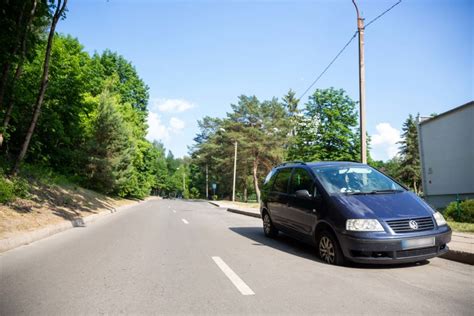 Tematinė nuotrauka: sugadintas automobilio ratas kelio duobėje arba automobilis su įjungtomis avarinėmis šviesomis prie duobės kelyje